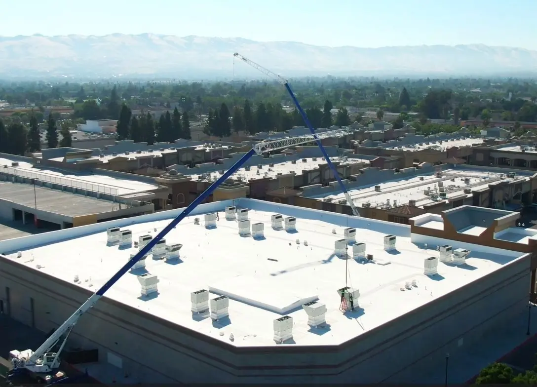 Aerial view of a crane lifting HVAC equipment onto a Bay Area shopping center roof