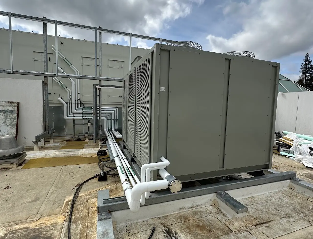 Rooftop packaged HVAC unit with refrigerant piping on a Bay Area commercial roof