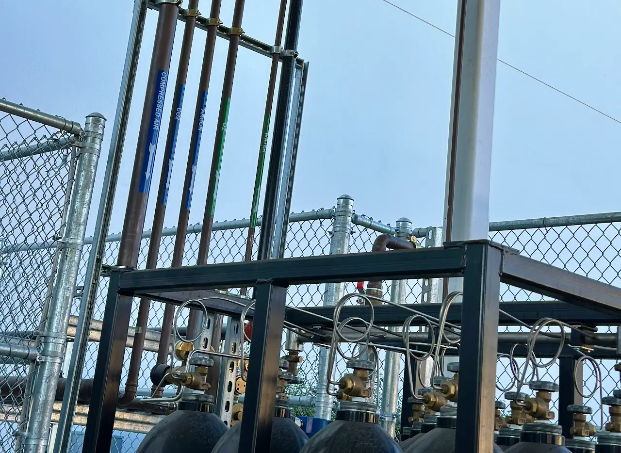Specialty gas cylinder rack and manifold feeding a semiconductor process piping system