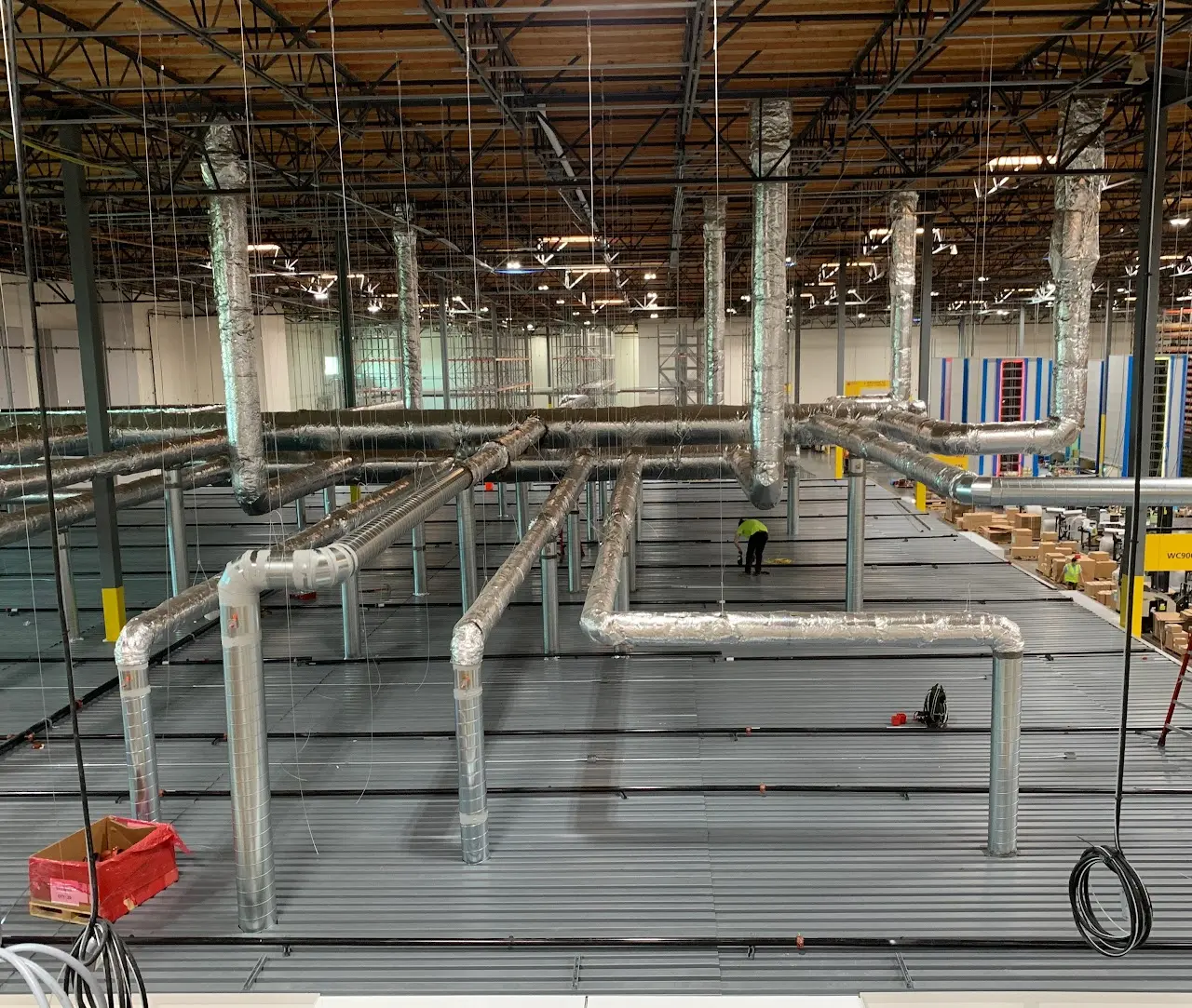 Overhead spiral HVAC ductwork installed across a large Bay Area warehouse